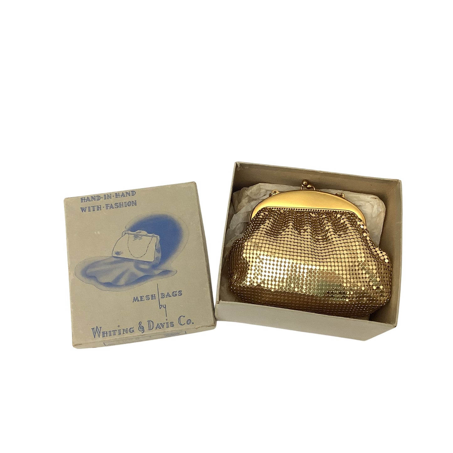 A Whiting & Davis vintage gold mesh kiss-lock clutch purse displayed inside its open beige presentation box next to its illustrated lid, on a plain white background.