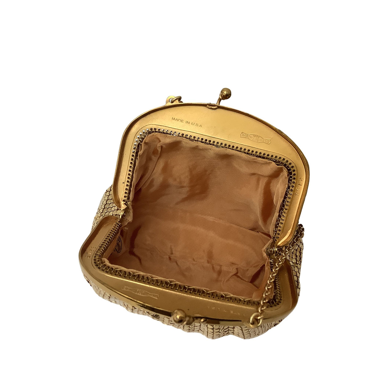 An open vintage Whiting & Davis metallic clutch purse with a gold-tone frame, patterned exterior, and tan rayon lining, shown on a plain white background.
