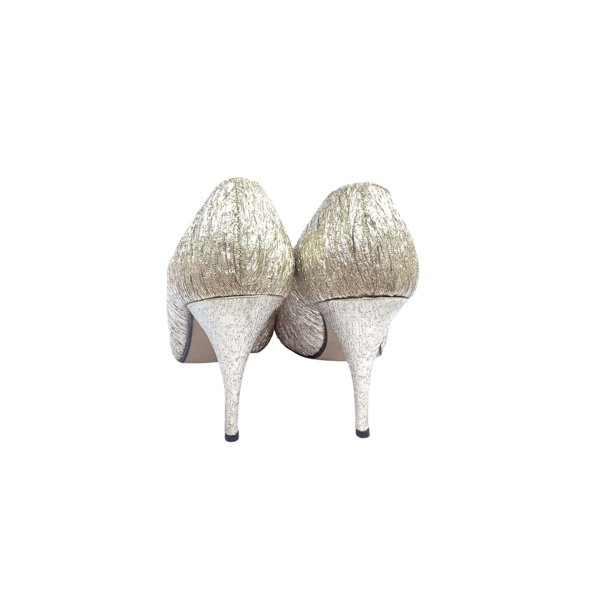 Pair of Wild Nights gold high-heeled pump shoes back view on a white background