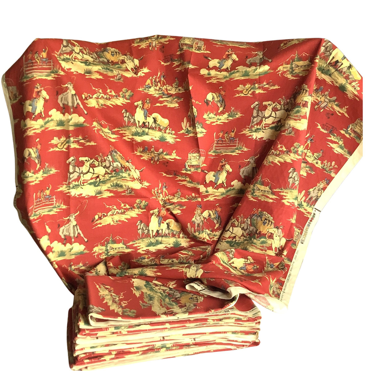 Overview of vintage folded red southwestern fabric yardage featuring figures, horses, and landscape scenes in beige, green, and blue, displayed against a white background.